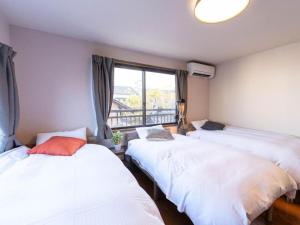 two beds in a room with a window at ゲストハウス あぽわん 貸切宿無料駐車場 in Mitoyo