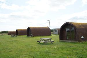 a group of huts and a picnic table in a field at Broomfields Glamping Pods in Whitby