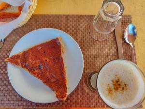 a slice of pizza on a white plate next to a cup at Musafir Desert Camp Jaisalmer in Jaisalmer