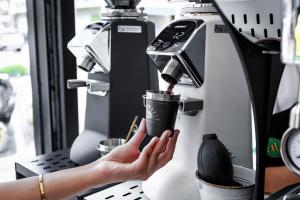 a woman holding a cup in a coffee machine at JB Old Town Stay in Ban Lo Long
