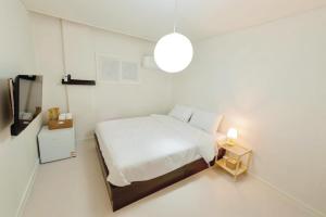 a white bedroom with a bed and a night stand at 브릭스테이 brikstay in Gyeongju