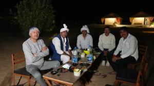 a group of people are sitting around a table at Rumis Desert Camp in Jaisalmer