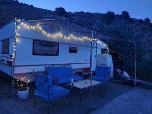 an rv with chairs and lights on it at night at Private caravan with mountain and sea view in Guájar-Faragüit +6 photos