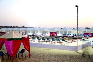 a pool with chairs and umbrellas on the beach at Musafir Desert Camp Jaisalmer in Jaisalmer +6 photos