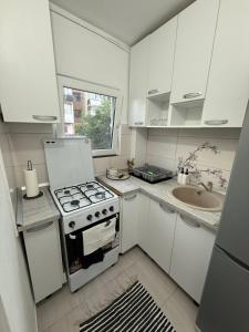 a white kitchen with a stove and a sink at Home Studio Arad in Arad +4 photos