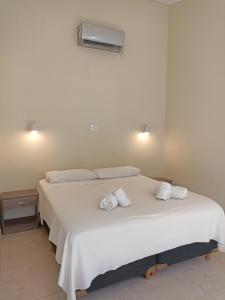 a bedroom with a white bed with towels on it at La hora azul departamentos in Playas Doradas