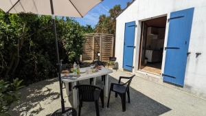 a table with chairs and an umbrella on a patio at La maison de papy près de la plage in Barbâtre