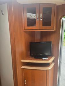 a tv in a wooden cabinet with a tv in it at Tabber Trolltunga caravan in Odda