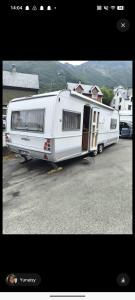 a white trailer parked in a parking lot at Tabber Trolltunga caravan in Odda