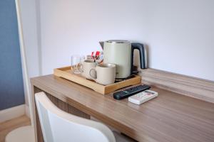 a table with a coffee pot and cups and a remote control at Hotel Boutique La Brisa in Vilanova i la Geltrú