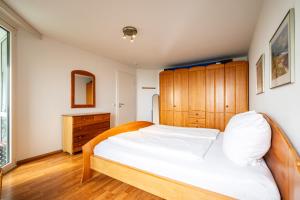 a bedroom with a large bed and a wooden cabinet at Gemütliche Ferienwohnung mit Wintergarten & Meerblick am Südstrand Wohnung 123 in Wilhelmshaven