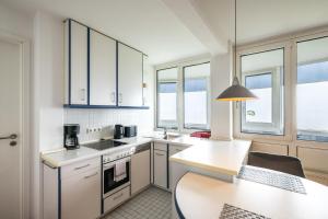 a kitchen with white cabinets and a table and a counter at Gemütliche Ferienwohnung mit Wintergarten & Meerblick am Südstrand Wohnung 123 in Wilhelmshaven