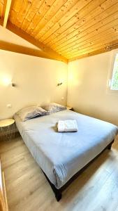 a large bed in a room with a wooden ceiling at Domaine des Epinettes in Saint-Romain-de-Jalionas