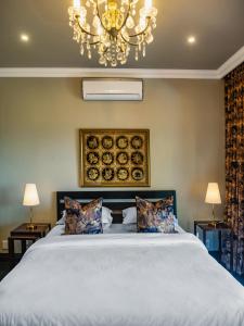 a bedroom with a large white bed with a chandelier at Luxury Villa Umdoni - Eden Rock Estate, Pennington in Pennington +16 photos