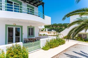 a white house with a green door and a palm tree at Cavo Plako Villas in Palekastron