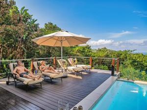 a group of people sitting on a deck next to a pool at Luxury Villa Umdoni - Eden Rock Estate, Pennington in Pennington