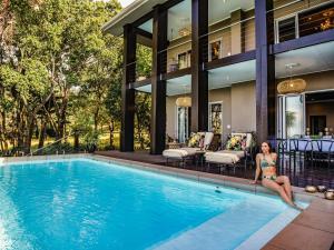 a woman sitting in the pool of a house at Luxury Villa Umdoni - Eden Rock Estate, Pennington in Pennington