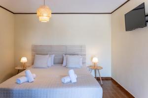 a bedroom with a bed with white pillows and a tv at Cavo Plako Villas in Palekastron +50 photos
