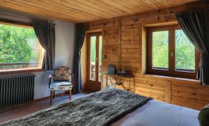a bedroom with a bed and a chair and windows at Chalet Cannelle in Châtel
