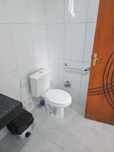 a bathroom with a white toilet and a wooden door at Pousada Mirantes Do Sincorá in Mucugê
