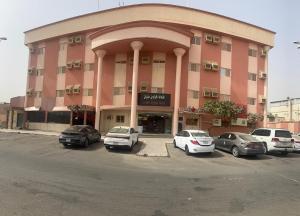 a large pink building with cars parked in a parking lot at فندق الكراون نجران نجمه in Najran