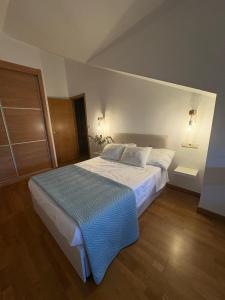 a bedroom with a large bed with a blue blanket at O Ático in Rosal