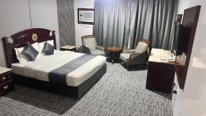 a hotel room with a bed and chairs and a television at فندق الكراون نجران نجمه in Najran