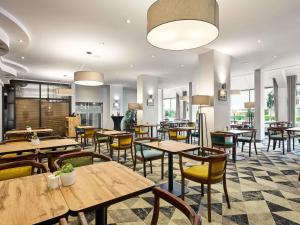 a restaurant with wooden tables and chairs and windows at Mercure Czestochowa Centrum in Częstochowa