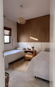 a bedroom with two beds and a night stand with a table at Wp White House- Estilo Grego 7 min do aqualinda in Andradina