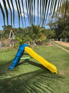 a yellow and blue slide on the grass at Pousada Recanto dos Buritis in Manhã