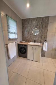 a bathroom with a washing machine and a sink at Beach cottage in Gonubie Park +13 photos