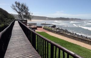 a wooden boardwalk leading to a beach with the ocean at Beach cottage in Gonubie Park