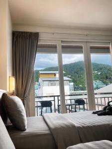 a bedroom with a bed and a large window at Doze Bangla in Patong Beach