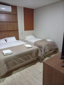 two beds in a hotel room with a tv at Terraza Frontera Hotel in Pedro Juan Caballero