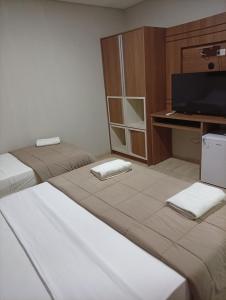 a room with two beds and a desk and a television at Terraza Frontera Hotel in Pedro Juan Caballero