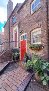 a brick house with a red door and some plants at Ironbridge View Townhouse - WINNER 2026 UK MOST PICTURESQUE SELF-CATERING HOLIDAY HOME & 2026 SELF-CATERING ACCOMMODATION OF THE YEAR in Ironbridge +51 photos