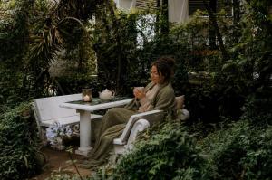 a woman sitting on a bench with a cup of coffee at De Haven Oost in Rayton