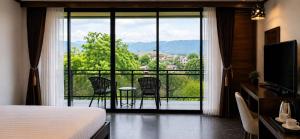 a room with a bed and a balcony with chairs at Chomphu Phukha Resort-Mountain View Nan in Pua