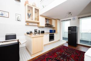 a kitchen with a black refrigerator and a red rug at Exklusive Ferienwohnung am Südstrand mit Panoramabalkon & Meerblick Wohnung 92 in Wilhelmshaven