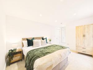 a white bedroom with a large bed and a dresser at NEW Artisan Apartment by Signature Stays - Modern - Spacious - Parking in Cheltenham