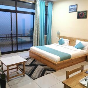 a bedroom with a bed and a large window at Rudraa Himalayan Retreat in Hawālbāgh