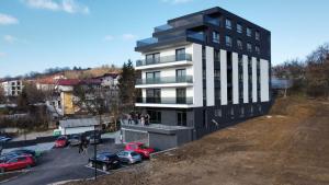 a building on a hill with cars parked in a parking lot at Soliq Stay App in Tuzla