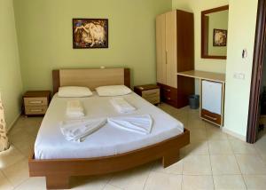 a bedroom with a large bed with white sheets at Dhimitri Rooms in Gjilek
