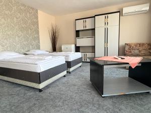 a room with three beds and a desk and a cabinet at Patyi Étterem és Hotel in Bögöte