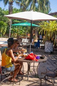 two women sitting at a table under an umbrella at Nopalero Hostel in Puerto Escondido
