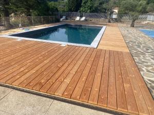 a pool with a wooden deck in a backyard at Chalet10Ardèche in Les Vans
