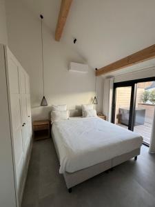 a bedroom with a white bed and a large window at Hartje Borgloon in Borgloon