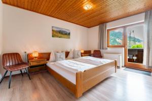 a bedroom with a bed and a chair and a window at Ferienhaus Pichl in Bruck an der Großglocknerstraße
