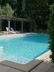 a large blue swimming pool with chairs and a gazebo at Domaine du Roujos - Gite Ocre in Beaumont-de-Lomagne +5 photos