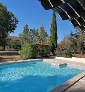 a swimming pool with blue water in a yard at Domaine du Roujos - Gite Ocre in Beaumont-de-Lomagne